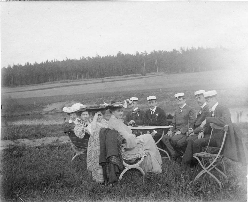 studenter-kvinnor-och-man-sittande-vid-bord-ute-pa-gras-skog-i-bakgrunden-sannolikt-ba6b5d-1024